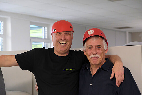 Zwei Kollegen vor dem Plattenbelichter mit Helm