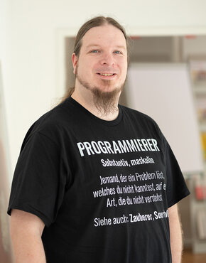 Mann mit Developer-T-Shirt, der in die Kamera lacht