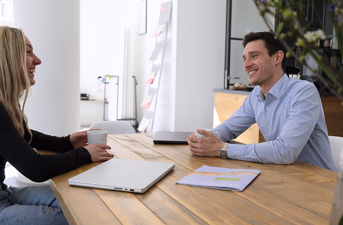 Zwei Menschen sitzen am Tisch und lachen