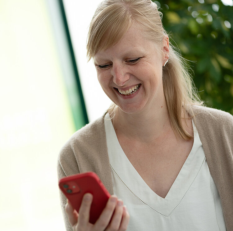 Frau, die lacht und auf ein Handy schaut