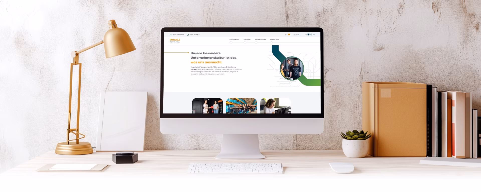 Ein iMac auf einem Schreibtisch zeigt die Webseite von Status-C
