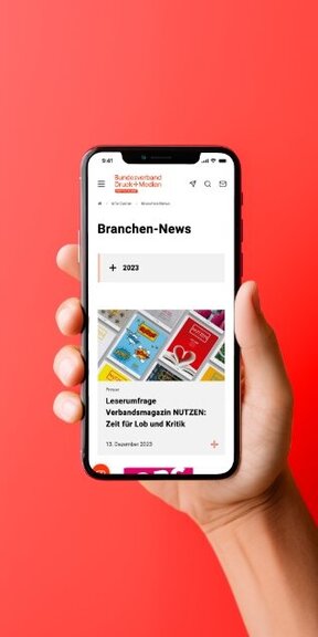 Vor einem farbigen Hintergrund hält eine Hand ein iPhone auf dem die mobile Webseite des Verbands Druck und Medien dargestellt wird