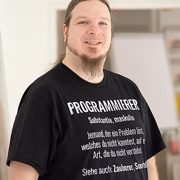 Mann mit Developer-T-Shirt, der in die Kamera lacht
