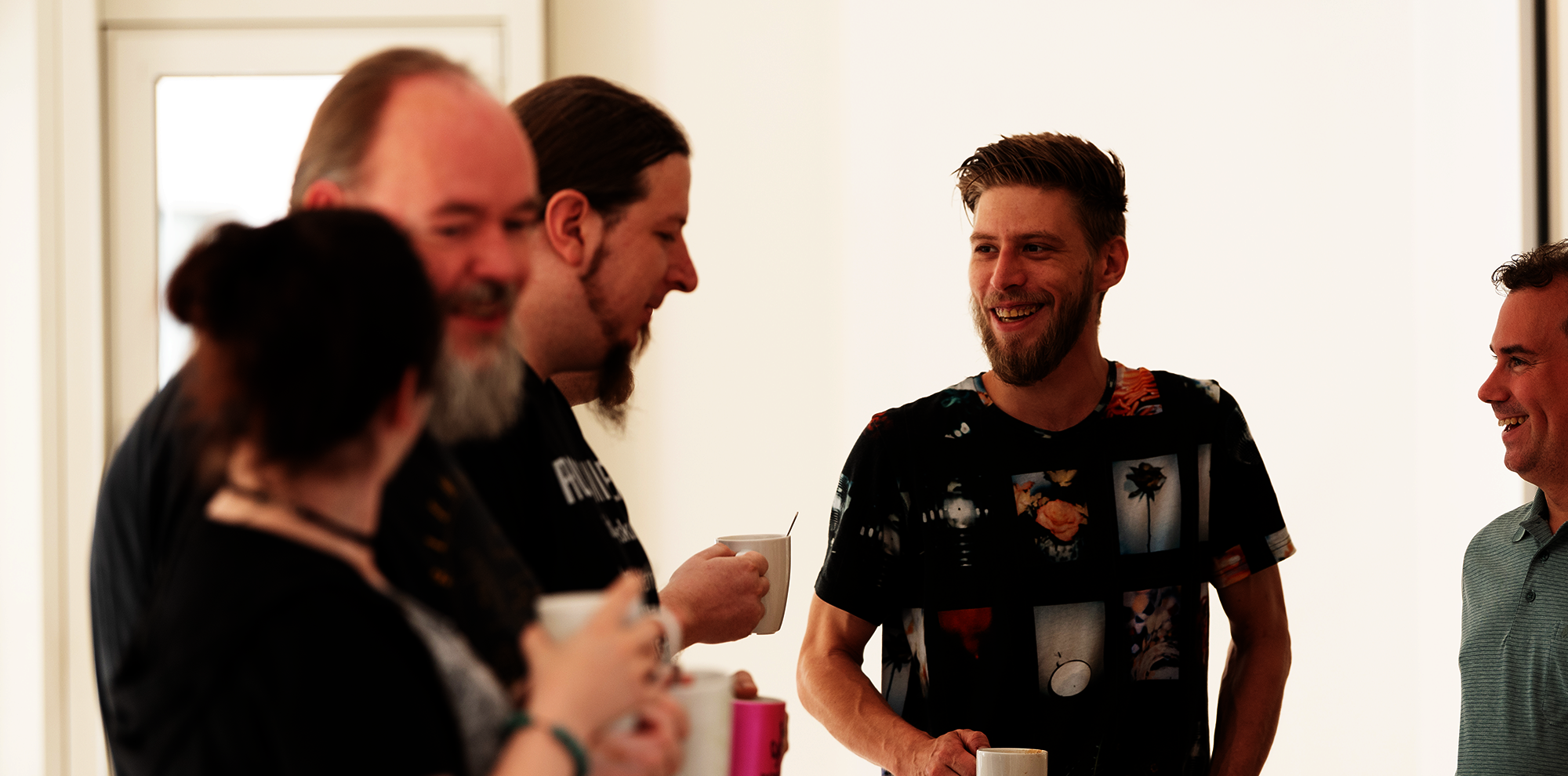 Team Eine Gruppe aus 5 Personen unterhalten sich fröhlich mit einer Tasse in der Hand