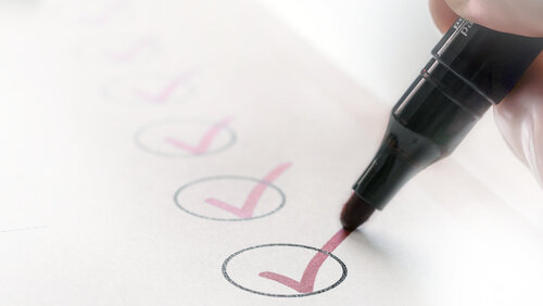 Das Bild zeigt ein Blatt mit einer Checkliste mit Häkchen und einem Stift.