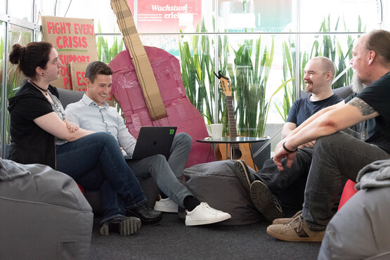 4 Personen, die auf Sitzsäcken sitzen, sich anschauen und lachen