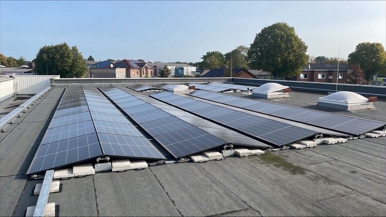 Photovoltaik-Anlage auf Flachdach bei Sonnenschein unter wolkenlosem Himmel