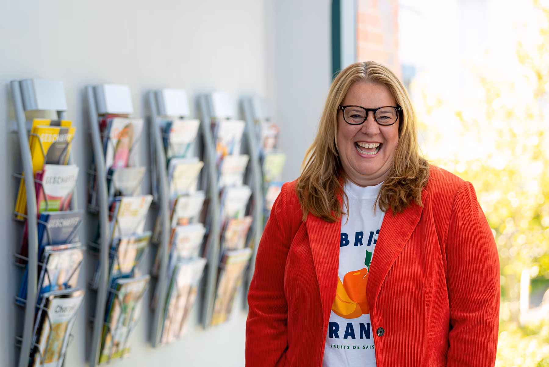 Lachende Frau vor Zeitschriftenständer