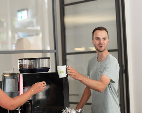 Mann, der vor einer Kaffeemaschine steht und überrascht aussieht