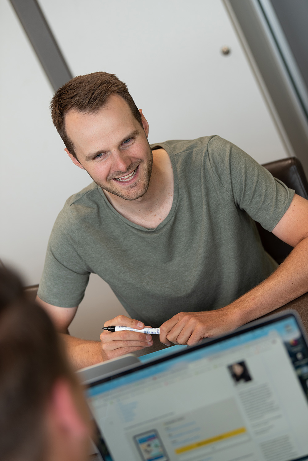 Mann sitzt am Tisch und lacht seinem Gegenüber zu