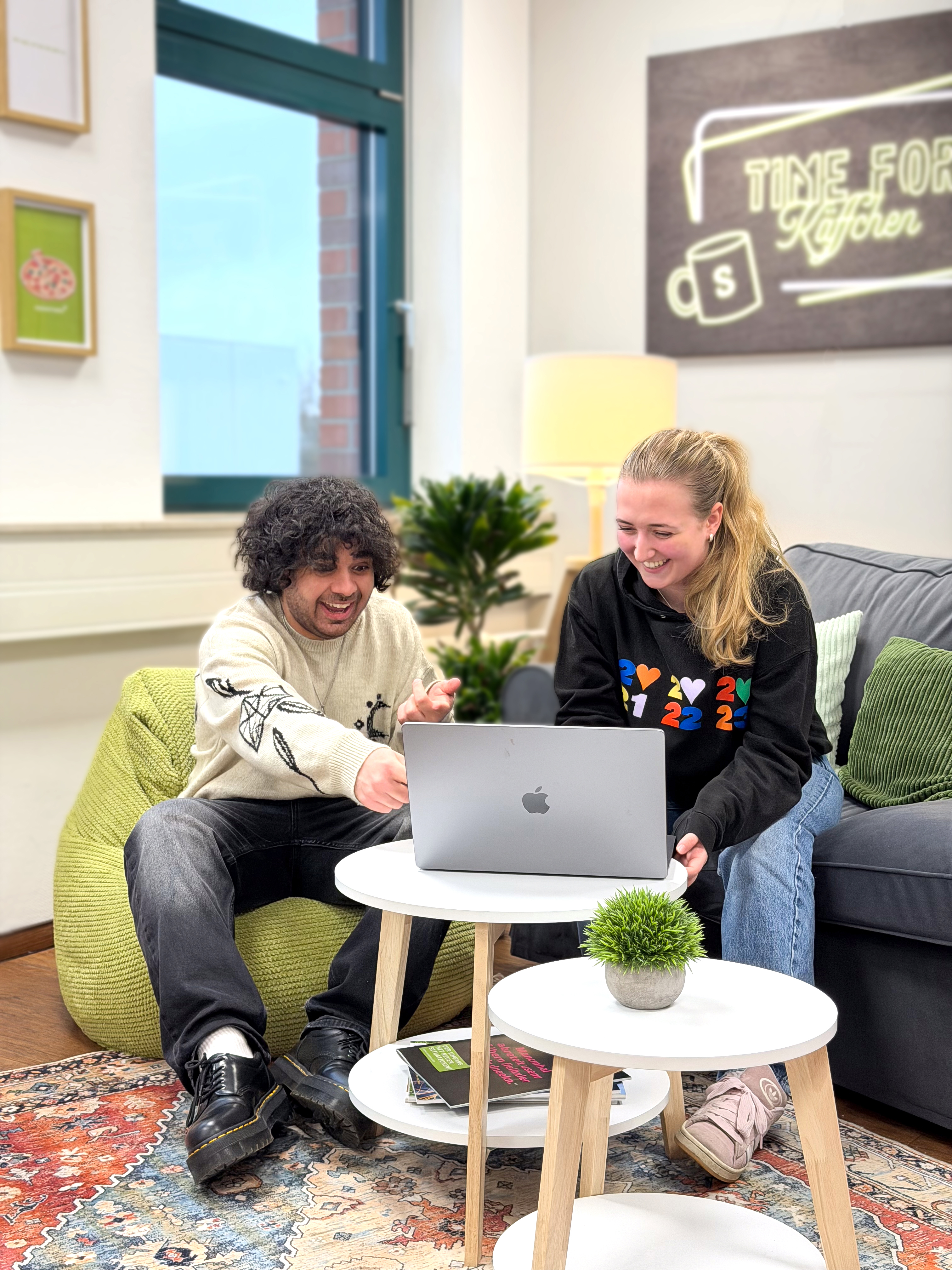 Zwei Kollegen schauen zusammen auf einen Bildschirm und sind begeistert.