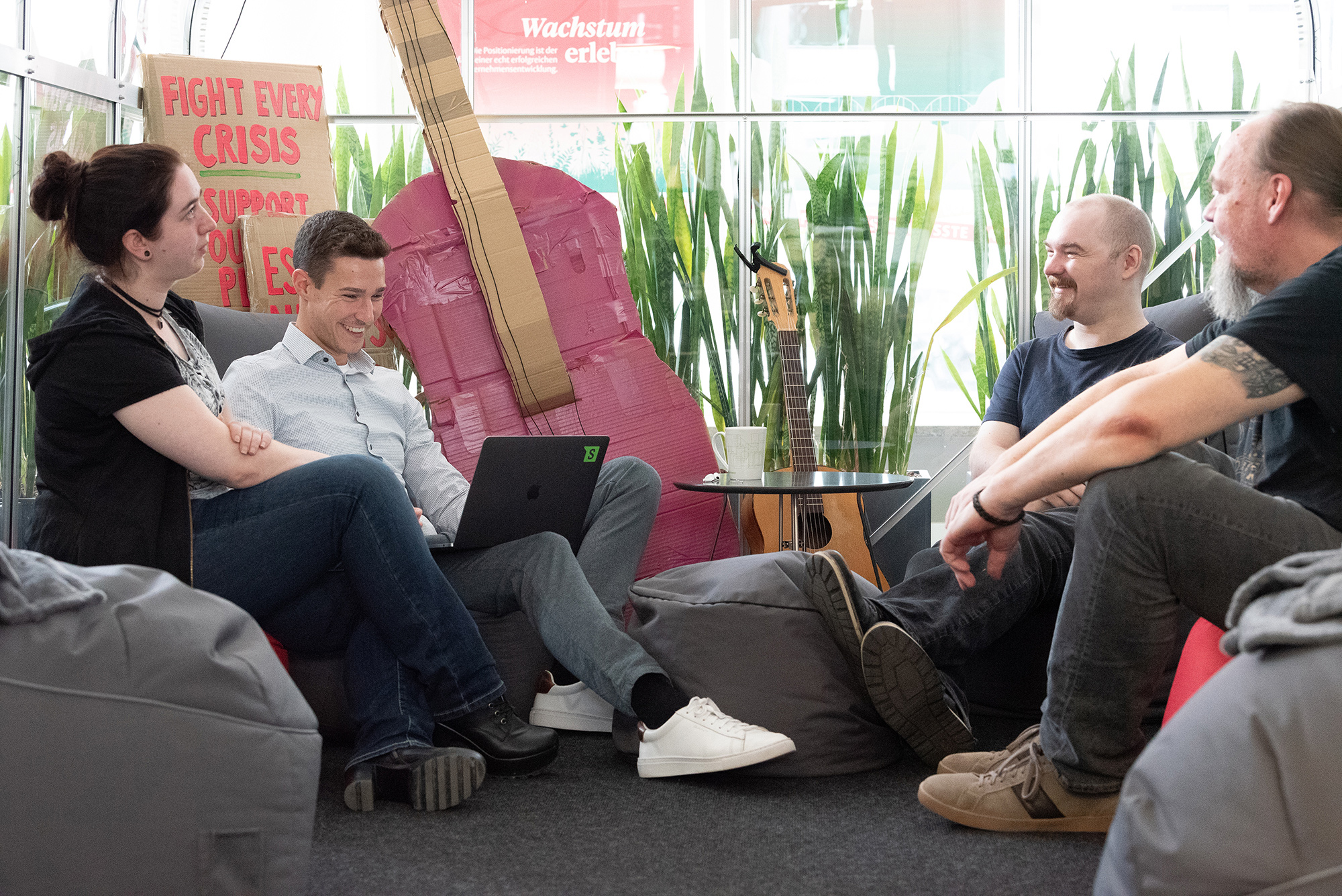 4 Personen, die auf Sitzsäcken sitzen, sich anschauen und lachen